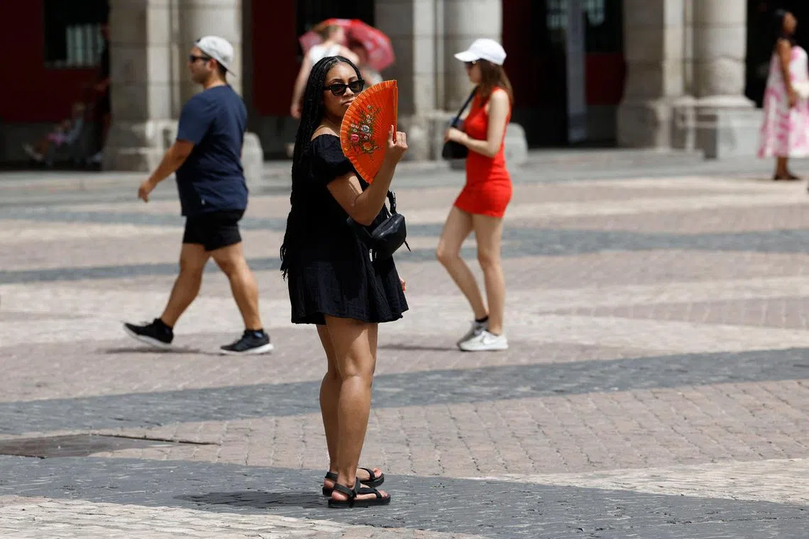 A woman fans herself to cool off in the midst of a heat wave in Madrid on August 9, 2023. Temperatures are expected to hit 44 degrees Centigrade (111 Fahrenheit) in Spain and Portugal today as the two countries boil under their third heatwave of the summer. With huge forest fires raging across southern Portugal for the fifth successive day, Spain's weather service warned that the average temperature across the country could hit a 70-year record. (Photo by JAVIER SORIANO / AFP)