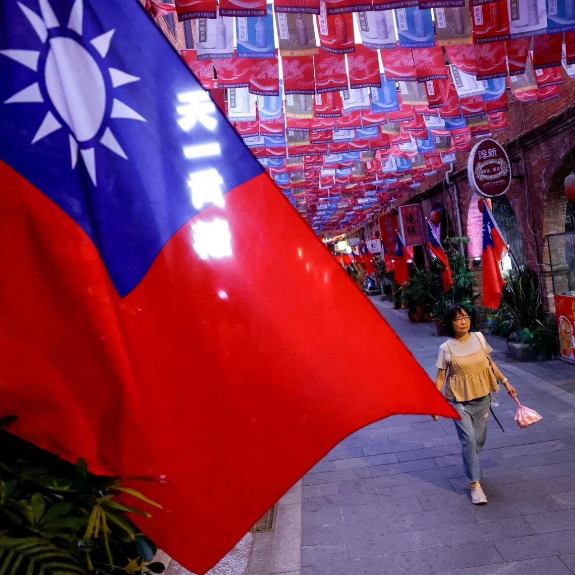 A woman walks past a street lined with Taiwanese flags, in Kinmen, Taiwan, October 19, 2025. REUTERS/Ann Wang