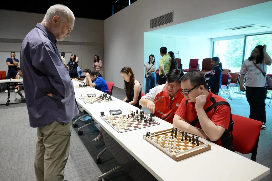 Chess grandmaster Thomas Luther (left) sparring with Edwin Tan. Tan, who has retinitis pigmentosa, is assisted by his coach, Mr. Louie Polistico (centre) and uses a braille board to play.