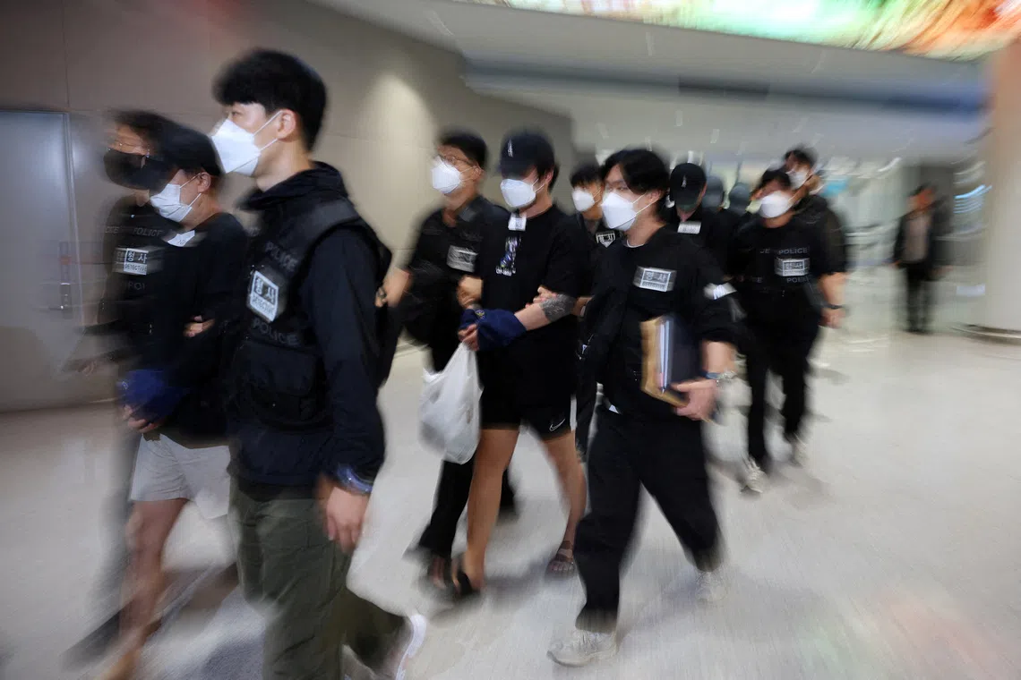 Police officers escort South Korean deportees suspected of being involved in online scam operations in Cambodia, upon their arrival at the Incheon International Airport on Oct 18.