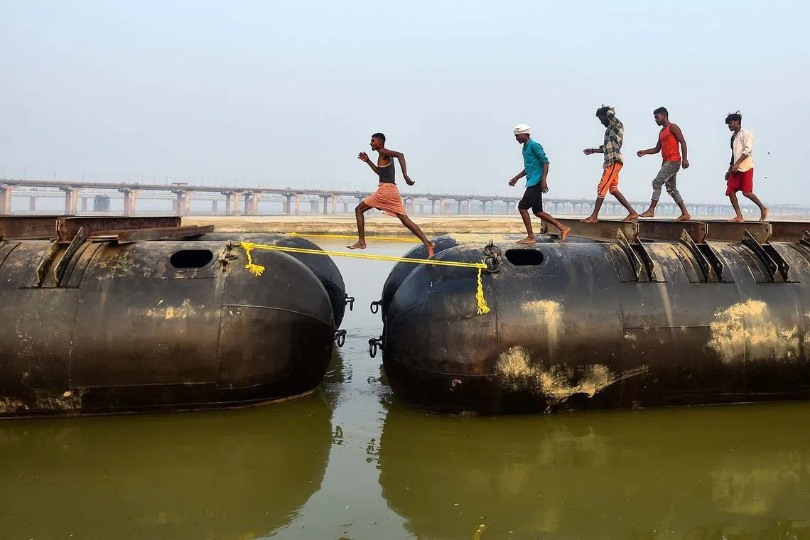 Labourers building a floating pontoon bridge ahead of the upcoming annual Hindu religious fair 'Magh Mela', along the shores of Ganges River in Prayagraj on Dec 4, 2023. 