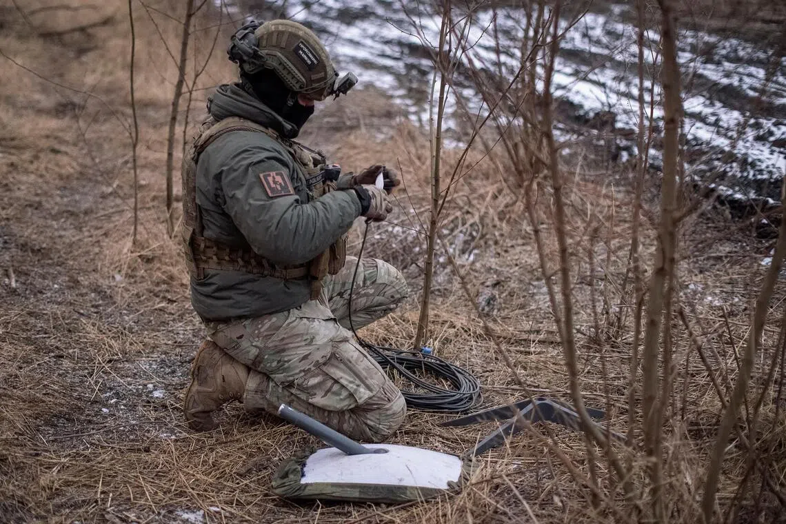 A Ukrainian serviceman prepares a Starlink satellite internet system at his front-line position, amid Russia’s invasion of Ukraine.