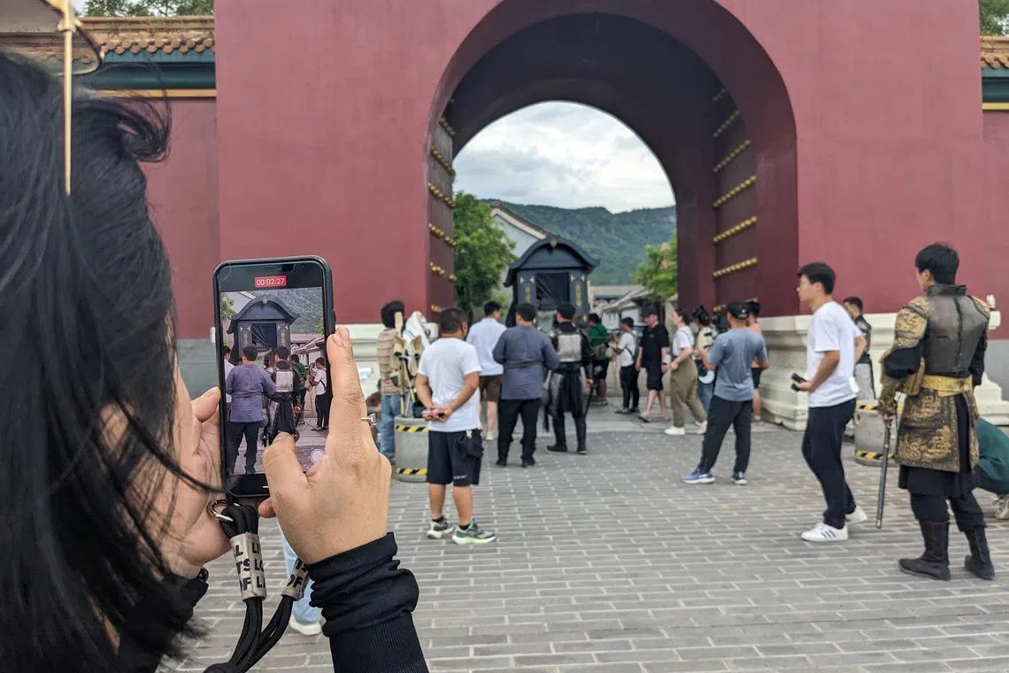 A visitor to the Palace of Ming and Qing Dynasties in Hengdian whips her phone out to capture a micro-drama film production at work. 