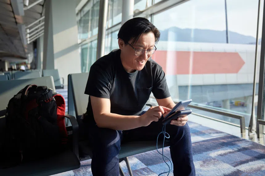 Best power bank in Singapore: Chinese man using phone with power bank at the airport