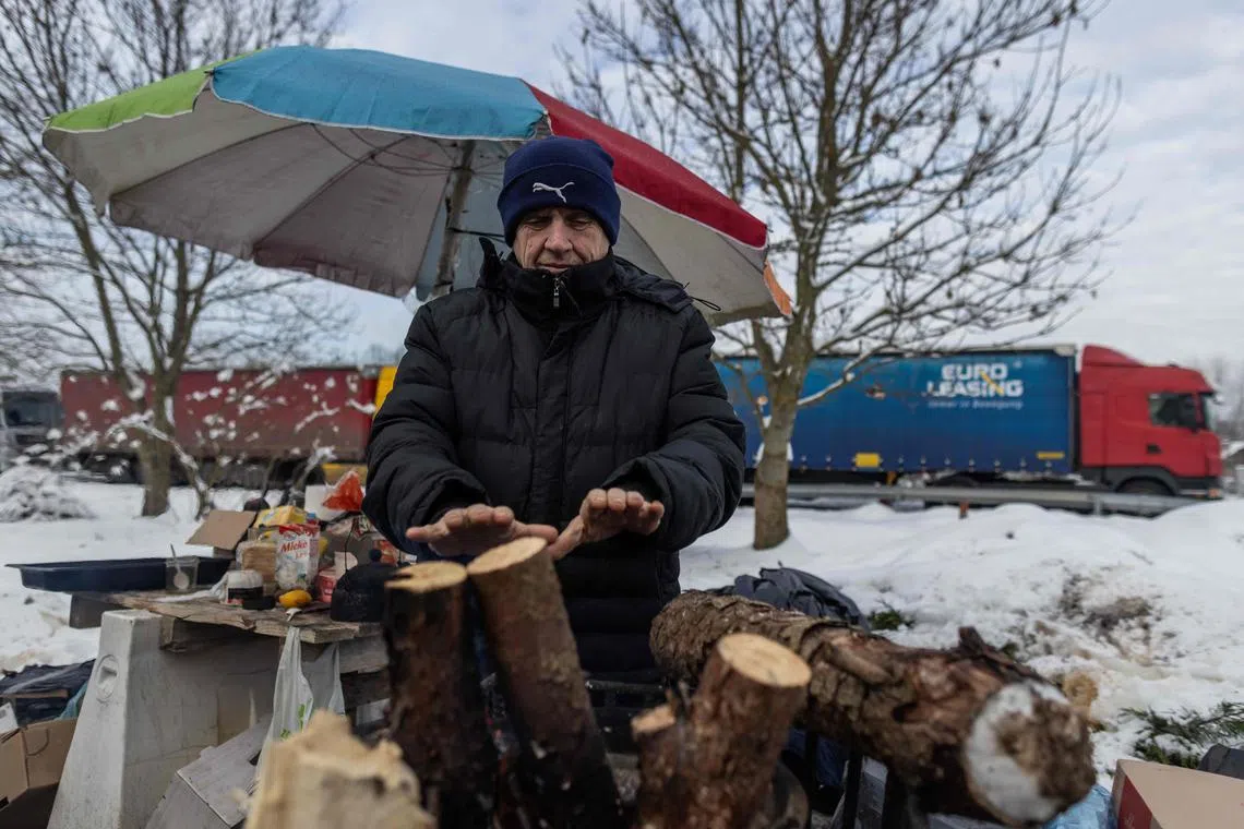 A Ukrainian truck driver warms up in a parking lot near the Polish-Ukrainian border crossing, amid a blockade by Polish truck drivers.