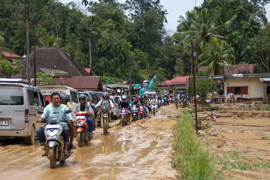 Motorists drive through a muddy road following flash flooding in Pesisir Selatan Regency, West Sumatra on March 9, 2024, after days of heavy rain across the province. At least 10 people were killed and 10 others were missing after flash floods and a landslide on the Indonesian island of Sumatra, a local official said on March 9. (Photo by REZAN SOLEH / AFP)