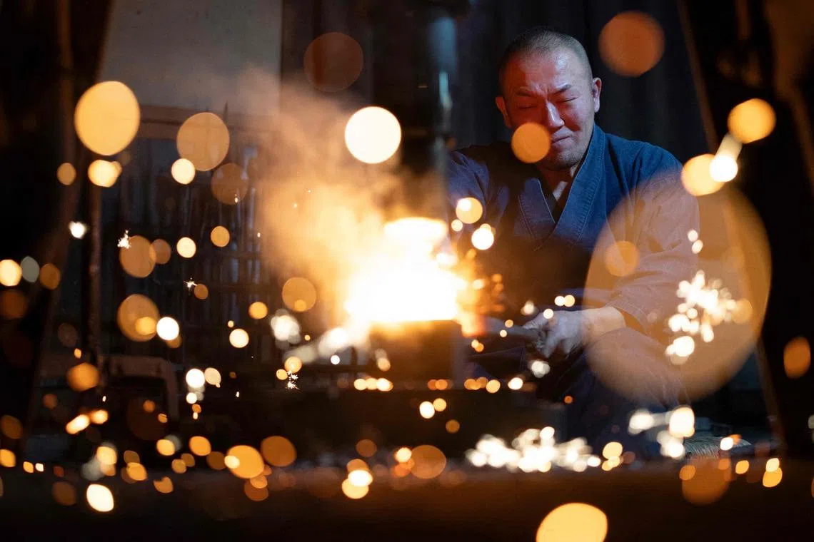 This picture taken on Jan 9, 2026 shows sparks flying as master swordsmith Akihira Kawasaki forges steel with a mechanical hammer at Kawasaki's workshop in Misato, Saitama prefecture, Japan. 