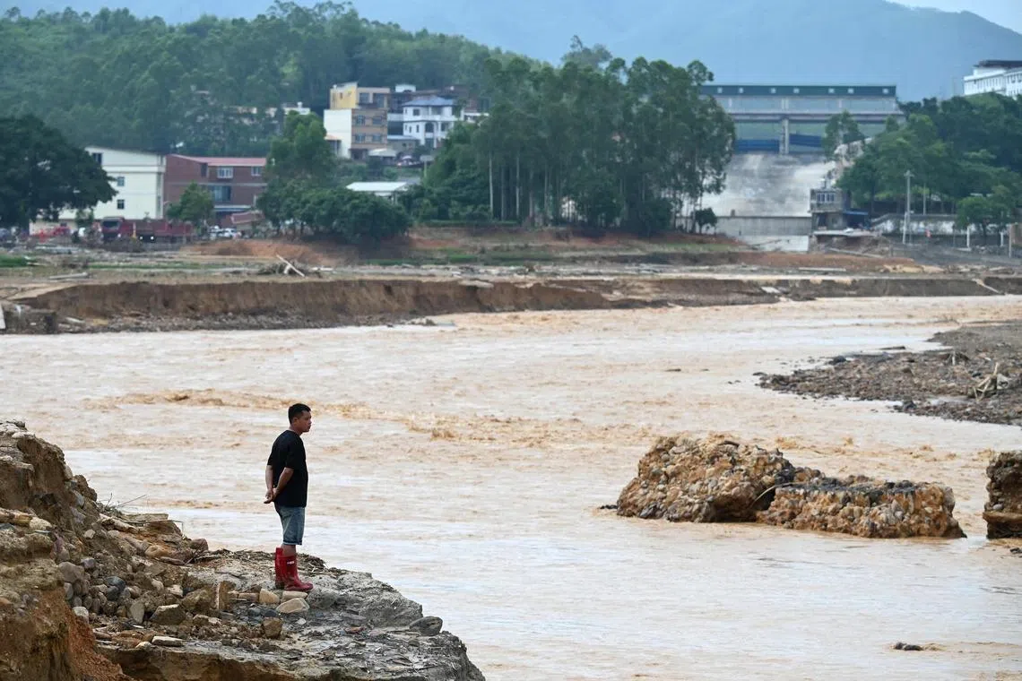 TOPSHOT - A man looks at water flowing from the collapsed Liulan reservoir in Liulan village in Hengzhou city, Chinas southwest Guangxi region, on July 8, 2026. Rescuers scoured flooded parts of China for survivors on July 8 after storms killed 17 people and caused dozens of rivers to overflow and a reservoir dam to burst, with officials warning of more rain. (Photo by GREG BAKER / AFP)