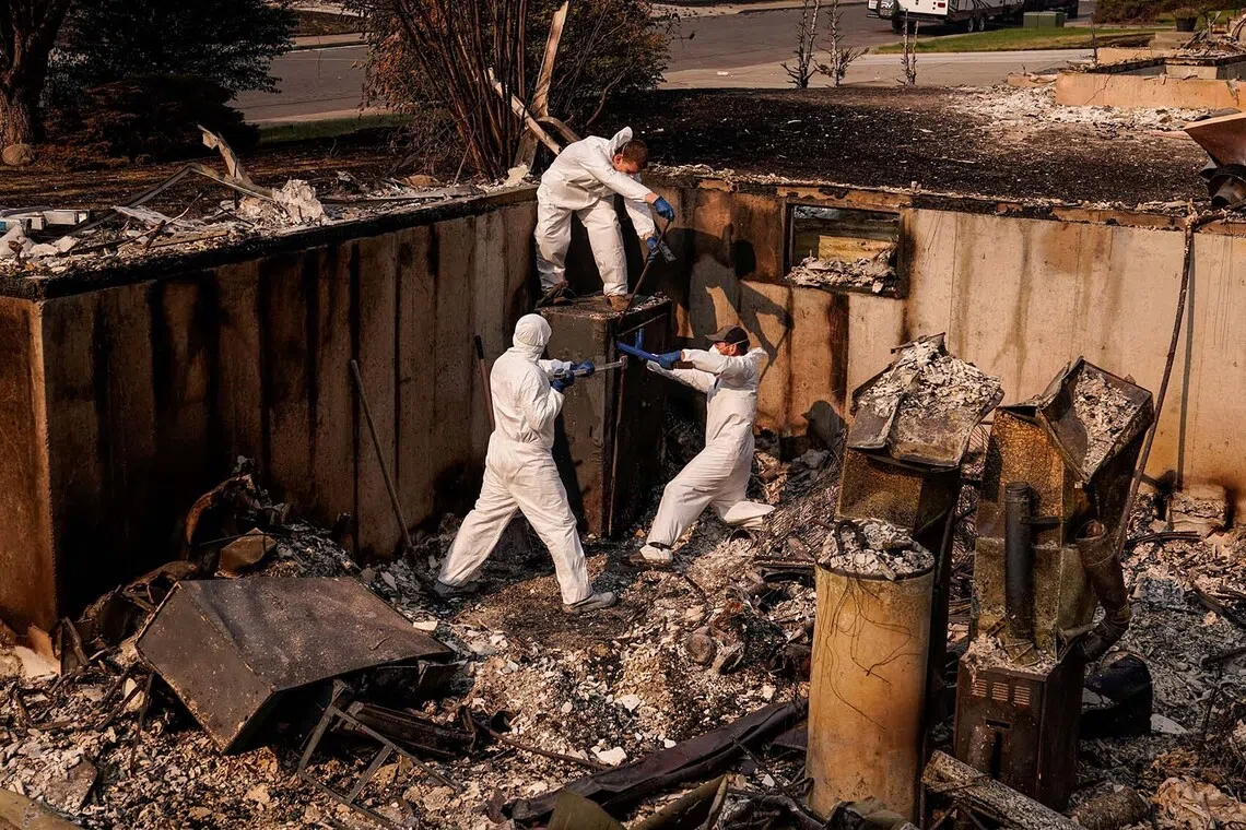 Jeff Clauson and his brothers, Brian Clauson and Bodey Clauson, try to open a safe as they recover items from Jeff's house which was burned by the Old Trails Fire wildfire, in Spokane, Washington, U.S., August 4, 2026. REUTERS/David Ryder TPX IMAGES OF THE DAY