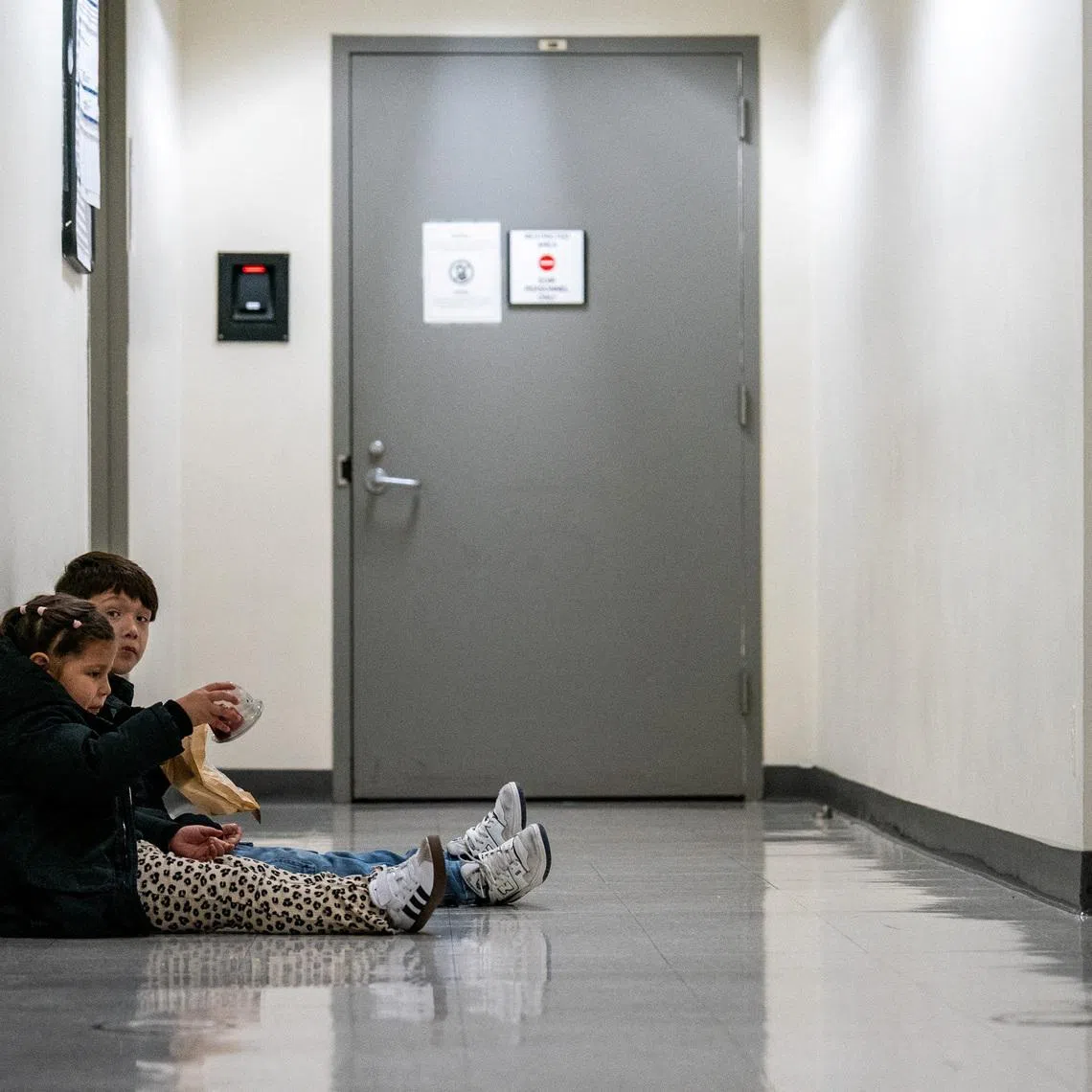 Two children sit in the hallway as their parents attend an immigration hearing at U.S. immigration court in Manhattan, in New York City, U.S., October 24, 2025. REUTERS/David 'Dee' Delgado