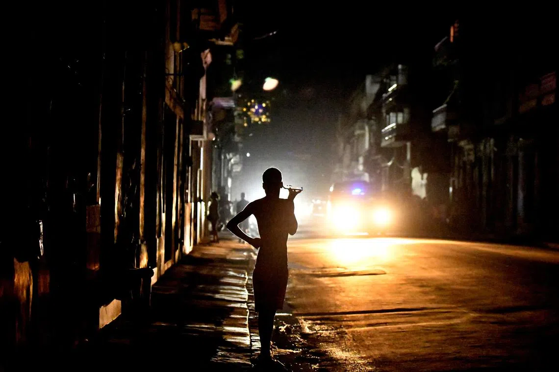 FILE PHOTO: People stand in the street at night as Cuba is hit by an island-wide blackout, in Havana, Cuba, October 18, 2024. REUTERS/Norlys Perez/File Photo