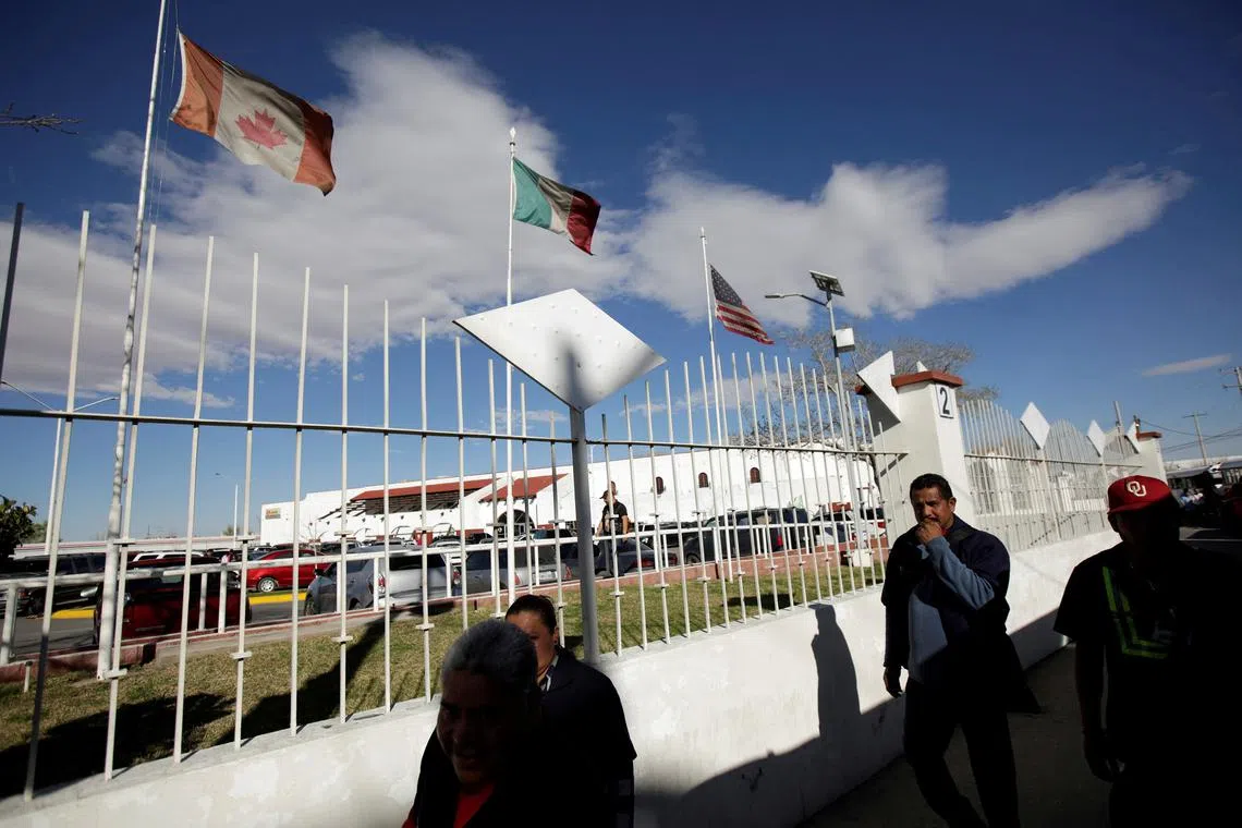 FILE PHOTO: Workers walk by the flags of Canada, Mexico and U.S. flying at an assembly factory in Ciudad Juarez, Mexico March 9, 2018. REUTERS/Jose Luis Gonzalez/File Photo
