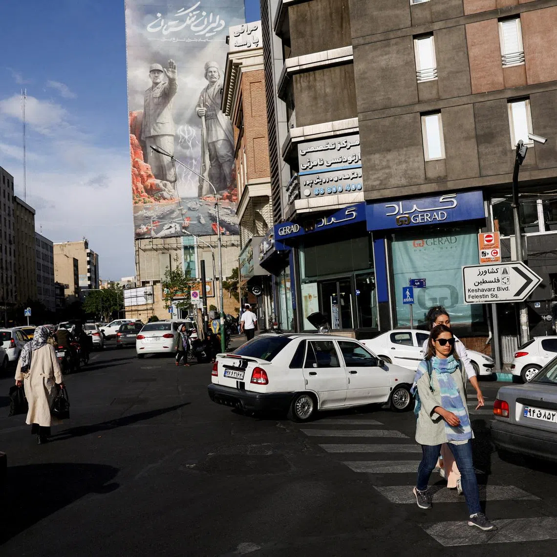 People walk past a billboard about the Strait of Hormuz, in Tehran, Iran, May 17, 2026.
