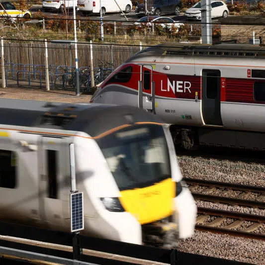 A train passes through Huntingdon Station, as the London North Eastern Railway (LNER) train, where a series of stabbings took place, remains on the platform.