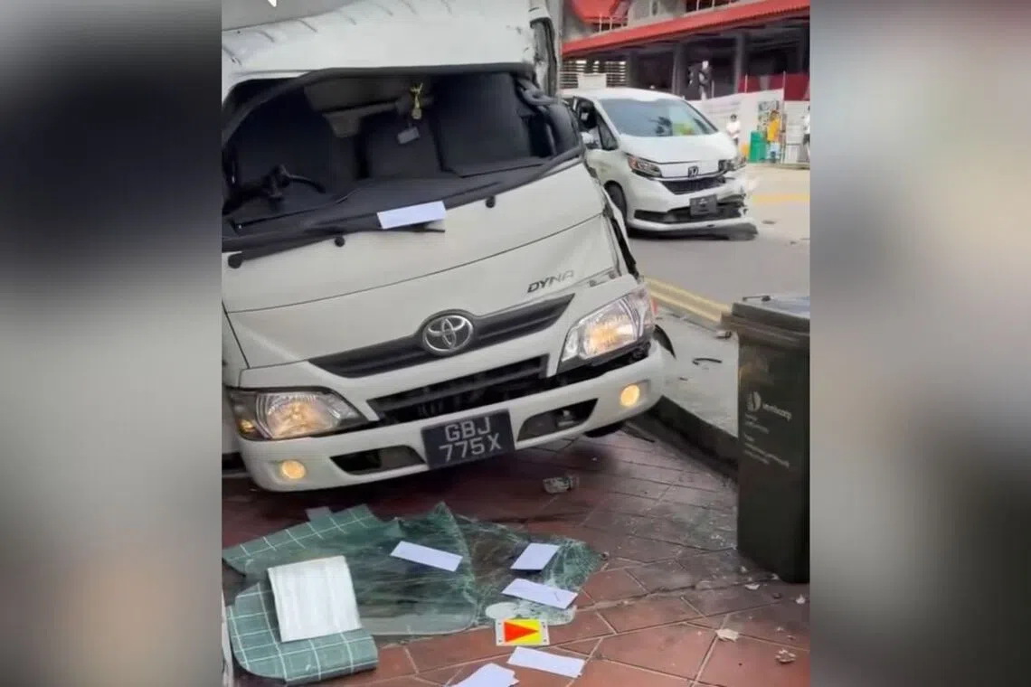The lorry appears to be off the road and on the pedestrian footpaths outside a row of shops.