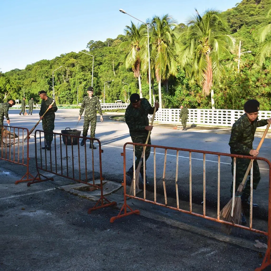 Military and police officers sweep a road in front of the old Khao Tanyong police station in Thailand’s southern province of Narathiwat, after an explosive device planted on a car was detonated overnight.