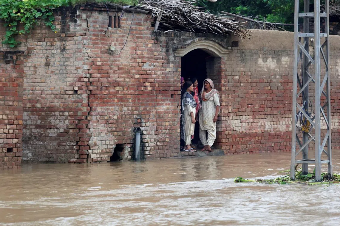 Residents stand at the entrance of a house on a flooded road, due to the monsoon rains and rising water level of the Sutlej River, in Hakuwala village near the Pakistan-India border in Kasur district of the Punjab province, Pakistan, August 24, 2025. REUTERS/Akhtar Soomro