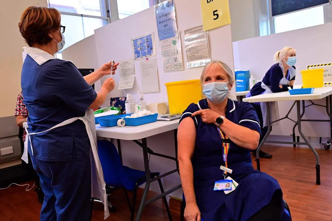A nurse (L) prepares to administer a Pfizer booster vaccine to at a vaccination centre in Derby, central England on Sept 20, 2021. Nurses will walk out on Thursday and the following Tuesday.