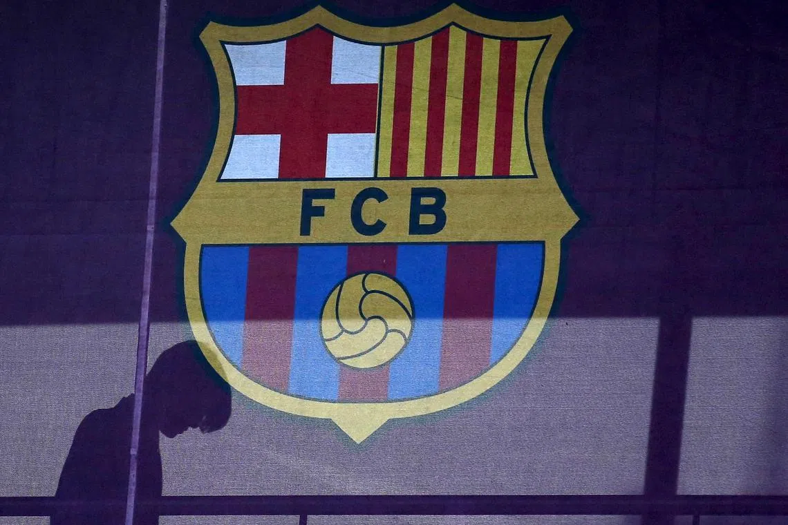 A silhouette of a woman walks past behind a FC Barcelona's logo at Camp Nou stadium in Barcelona, Spain, March 24, 2016. REUTERS/Albert Gea