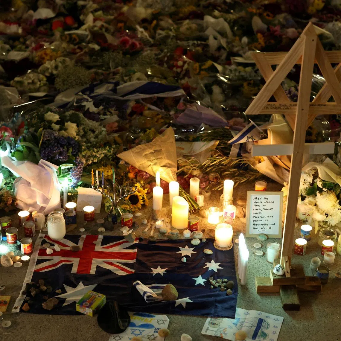 FILE PHOTO: An Australian flag sits amongst floral tributes honouring the victims of a shooting at Jewish holiday celebration on Sunday at Bondi Beach, in Sydney, Australia, December 16, 2025. REUTERS/Hollie Adams/File Photo