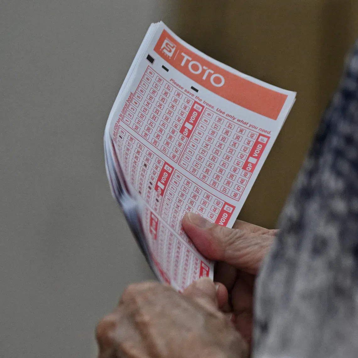 A woman holds her tickets while queueing on the last day to place bets for the TOTO Hong Bao Draw 2023, at the Singapore Pool Outlet at the Toa Payoh HDB Centre on Feb 3, 2023.