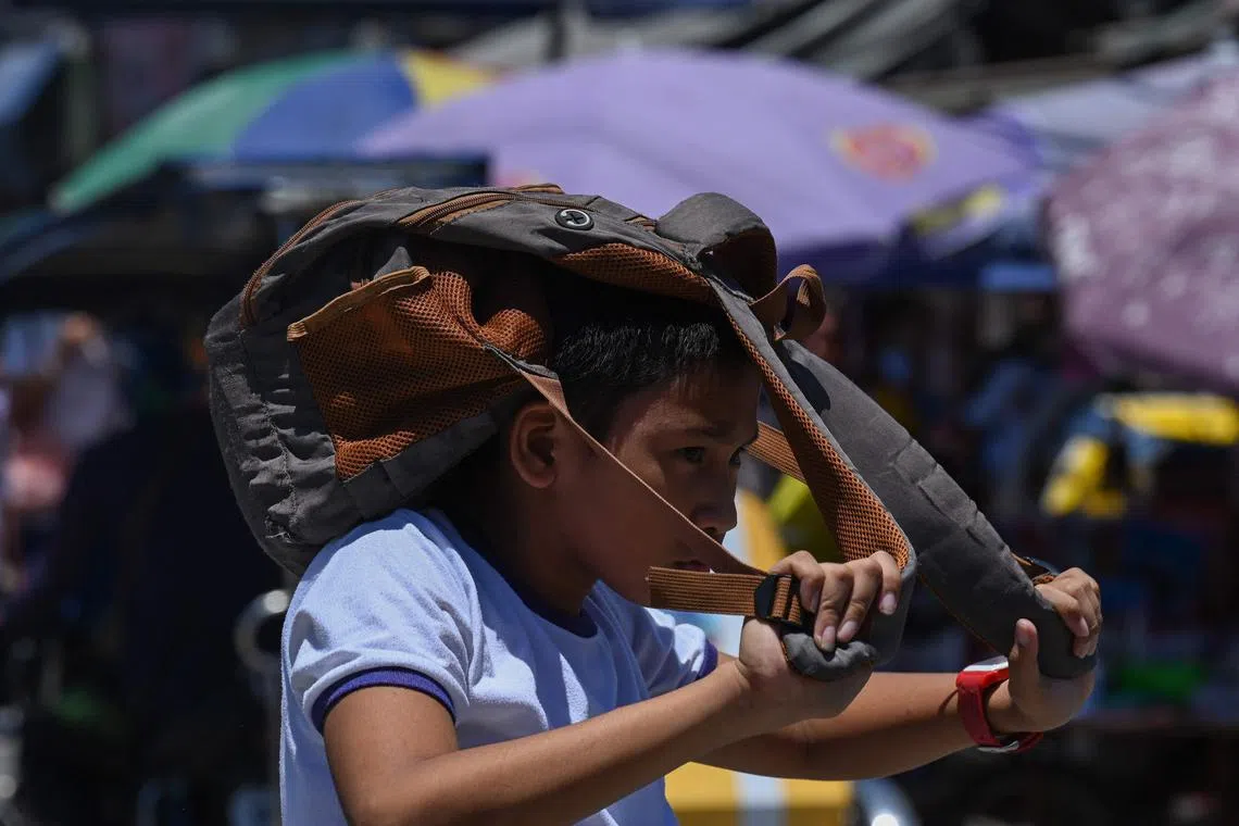 A student uses a bag to protect himself from the sun during a hot day in Manila on April 2.