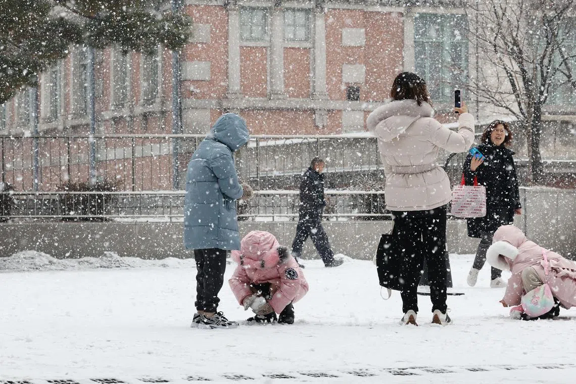 Children play in the snow in front of Seoul Station in South Korea.