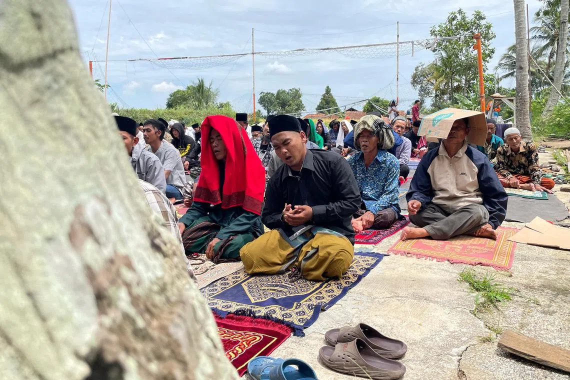 Muslim men pray during Friday prayers at a volleyball field, as their nearest mosque was damaged by the quake.