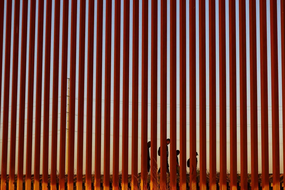 Migrants trying to reach the United States walking by a border wall in Ciudad Juarez, Mexico, as seen from El Paso, Texas, U.S. on May 8. Thousands of migrants in Mexico have been clambering onto dangerous freight trains rumbling northward in a scramble to reach the U.S. border by the time the United States ends a tough migration policy later this week. 