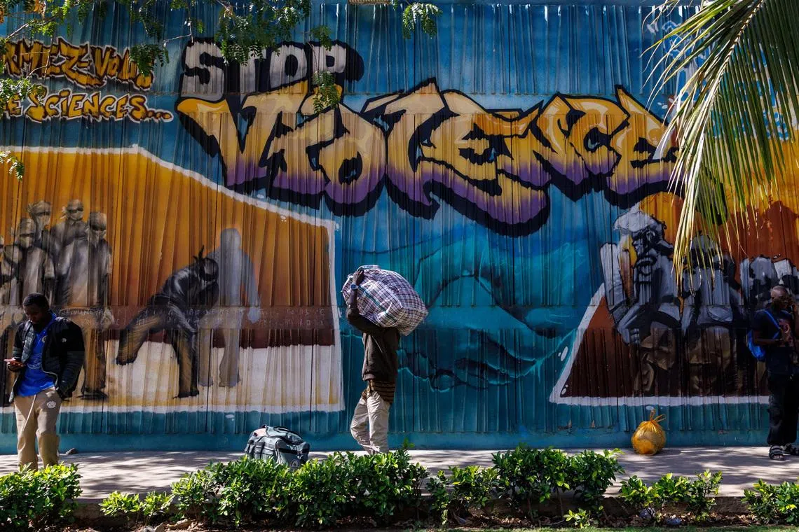 A student carries a bag with his belongings as he walks past a graffiti mural reading “Stop Violence” outside the Cheikh Anta Diop University campus that  was closed today until further notice after clashes with security forces left one student dead during protests in which demonstrators have been demanding stipends and other financial support amid the government’s ongoing fiscal challenges in Dakar, Senegal, February 10, 2026.REUTERS/Zohra Bensemra