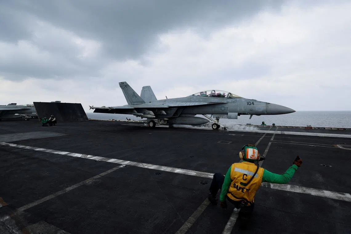 FILE PHOTO: A flight operating crew member signals a F/A-18E Super Hornet fighter jet on the flight deck of the USS Dwight D. Eisenhower (CVN 69) aircraft carrier in Southern Red Sea, Middle East, February 13, 2024. REUTERS/Hamad I Mohammed/File Photo
