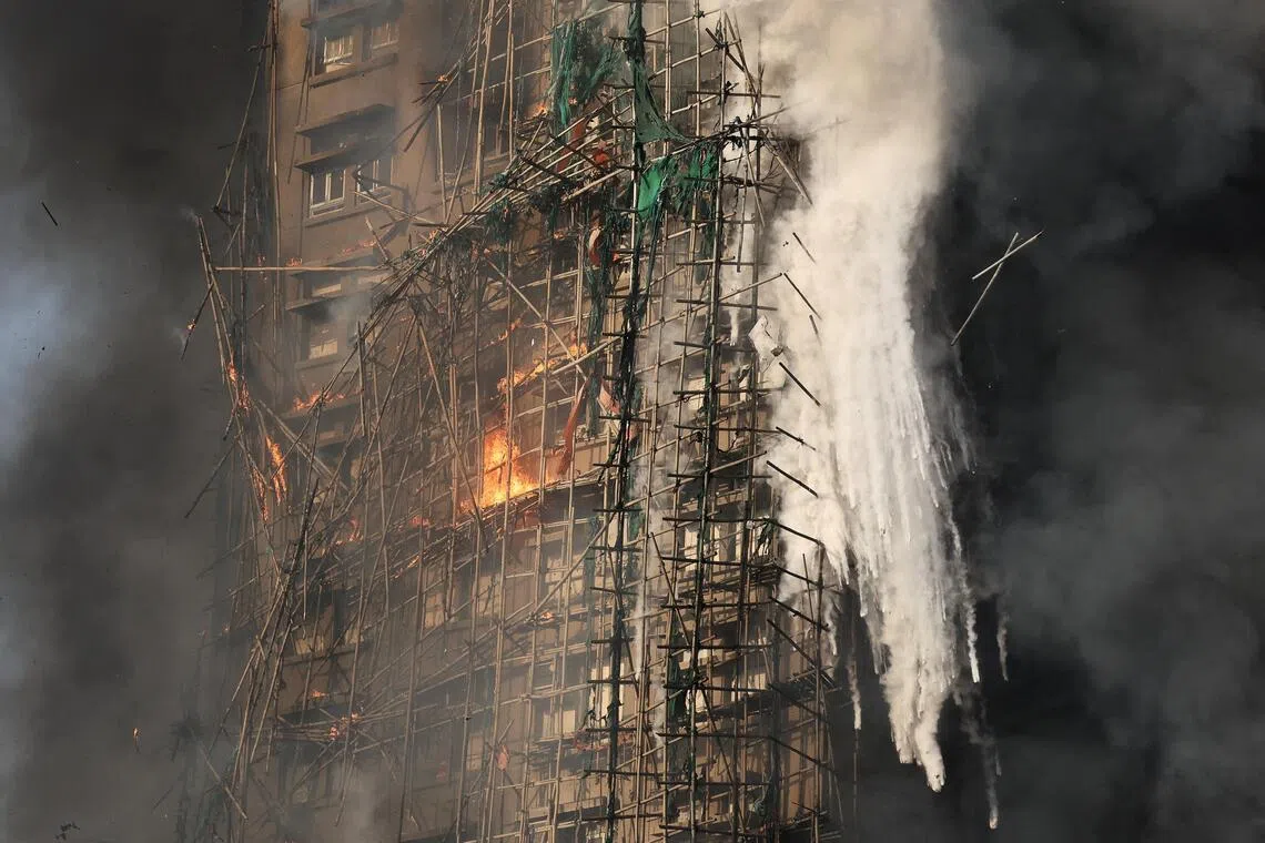Smoke rises while flames burn bamboo scaffolding on a building at Wang Fuk Court housing estate, in Tai Po, Hong Kong, China, November 26, 2025. REUTERS/Tyrone Siu