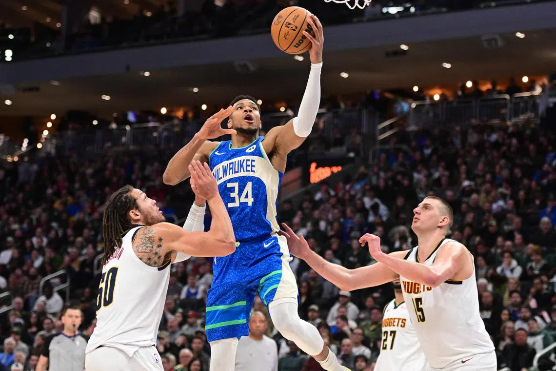Milwaukee Bucks forward Giannis Antetokounmpo taking a shot between Denver Nuggets forward Aaron Gordon (No. 50) and centre Nikola Jokic (No. 15) in the second quarter.