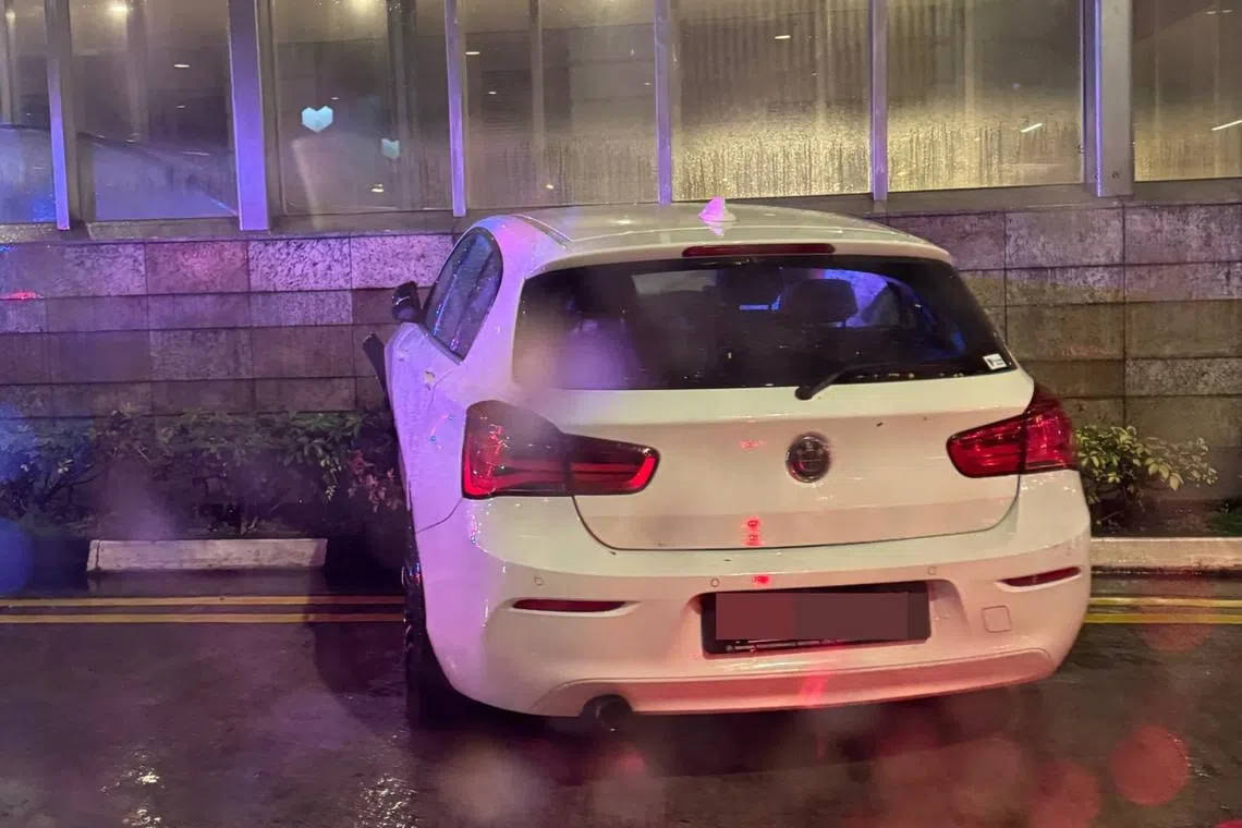 In a photo posted on Facebook, a white BMW car is seen with its front wheels mounted onto the kerb, in front of a building.