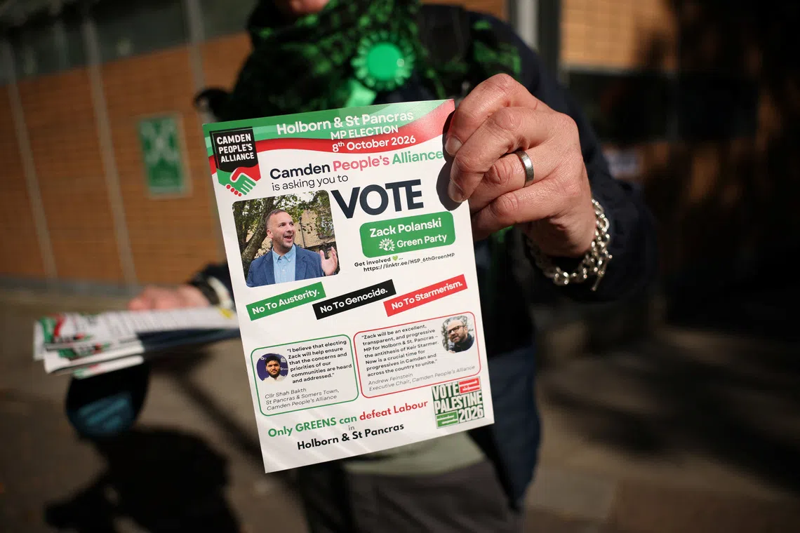 A Green Party supporter shows a flyer calling to vote for Zack Polanski as voters head to the polls in the Holborn and St Pancras by-election, triggered by the resignation of former Prime Minister Keir Starmer as MP for Holborn and St Pancras, in London, Britain, October 8, 2026. REUTERS/Isabel Infantes
