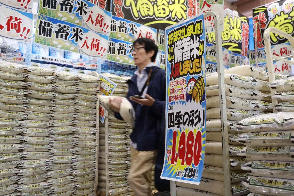 (FILES) A customer walks past sacks of rice, released by the government from its reserve under a discretionary contract, at a branch of Japanese discount retailer Don Quijote in Tokyo on June 1, 2025. Rice prices in Japan soared 99.2 percent in June year-on-year, official data showed on July 18, 2025, piling further pressure on Prime Minister Shigeru Ishiba ahead of elections this weekend. (Photo by JIJI PRESS / AFP) / Japan OUT