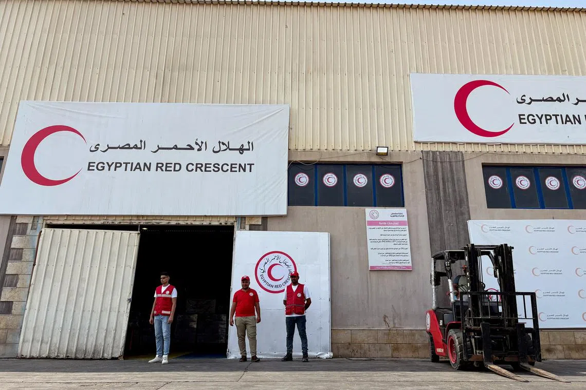 People stand in front of a warehouse for aid deliveries, waiting to be delivered to Gaza, at a logistics site outside Arish, Egypt, on Aug 11.