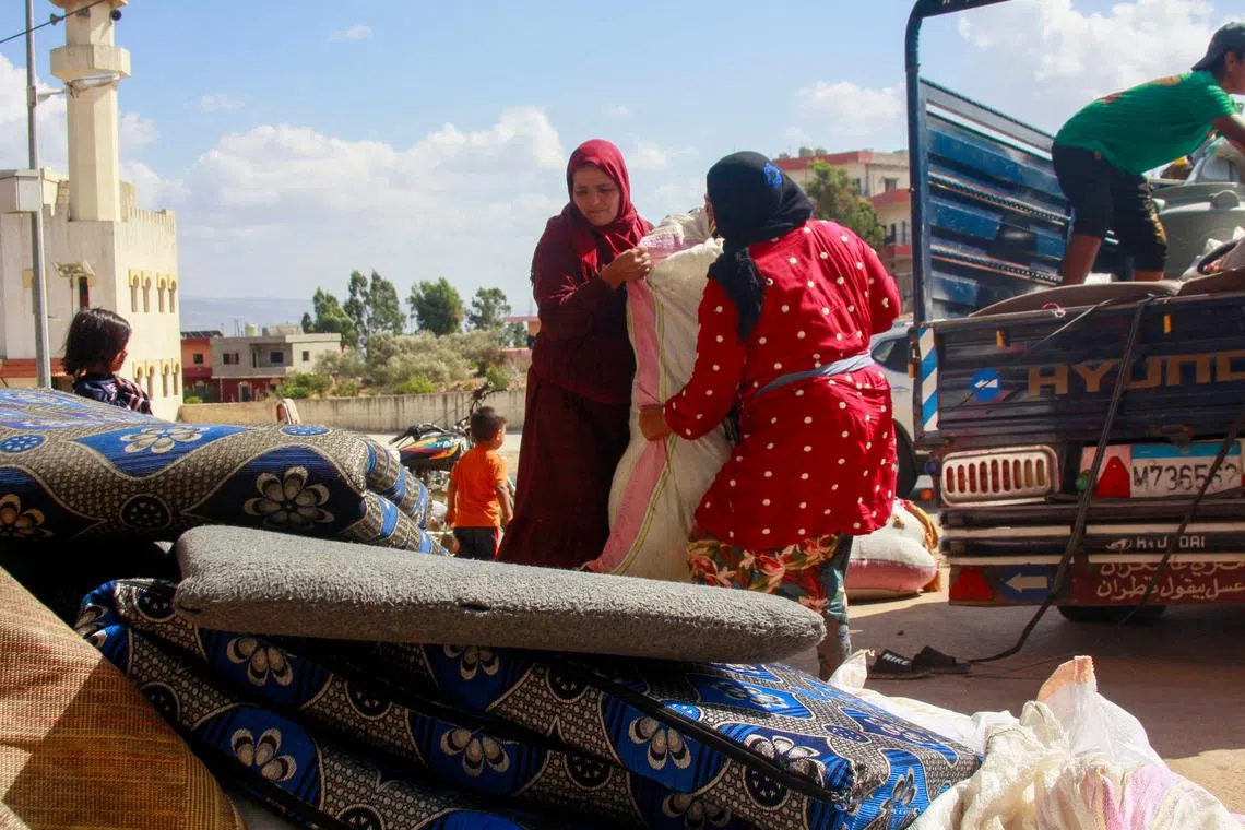 Syrian refugees load their belongings on a truck as they prepare to leave the southern Lebanese village of Wazzani after the Israeli army dropped leaflets calling for them to evacuate on September 15, 2024. (Photo by Rabih DAHER / AFP)