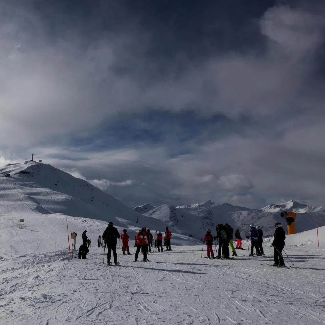 Skiers stand on a slope overlooking snow-covered mountains in Livigno, Italy, January 9, 2026. REUTERS/Yara Nardi