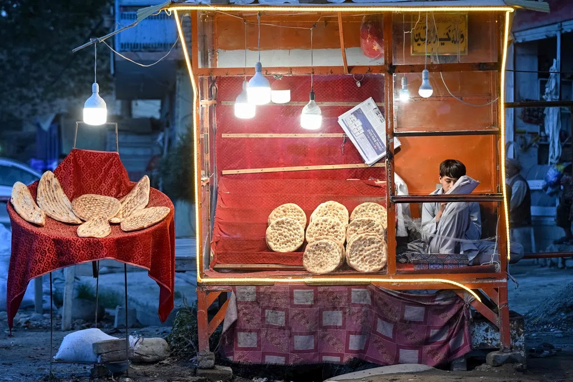 TOPSHOT - An Afghan boy selling bread sits in a stall in the Taloqan district of Afghanistan's Takhar province on September 28, 2026. (Photo by Omer ABRAR / AFP)