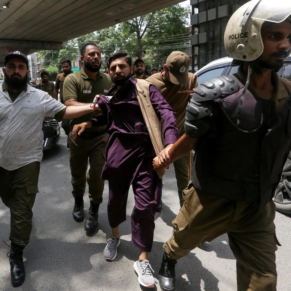 Police officers lead a detained supporter of Pakistan's former Prime Minister Imran Khan during a nationwide protest.