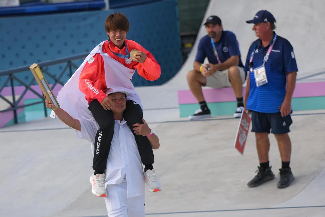 Yuto Horigome of Japan sits on the shoulders of his coach after winning the men’s skateboarding street final.