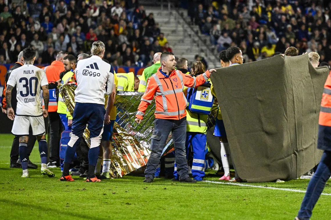 Players and personnel surrounding RKC Waalwijk goalkeeper Etienne Vaessen after his injury during the Dutch Eredivisie match between RKC Waalwijk and Ajax Amsterdam in Waalwijk on Saturday. After he was stretchered off, both teams went inside and after deliberations, the game was called off.