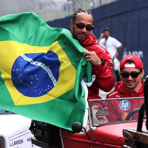 Ferrari's Lewis Hamilton holds a Brazil flag with Ferrari's Charles Leclerc and Aston Martin's Fernando Alonso during the drivers parade before the race.