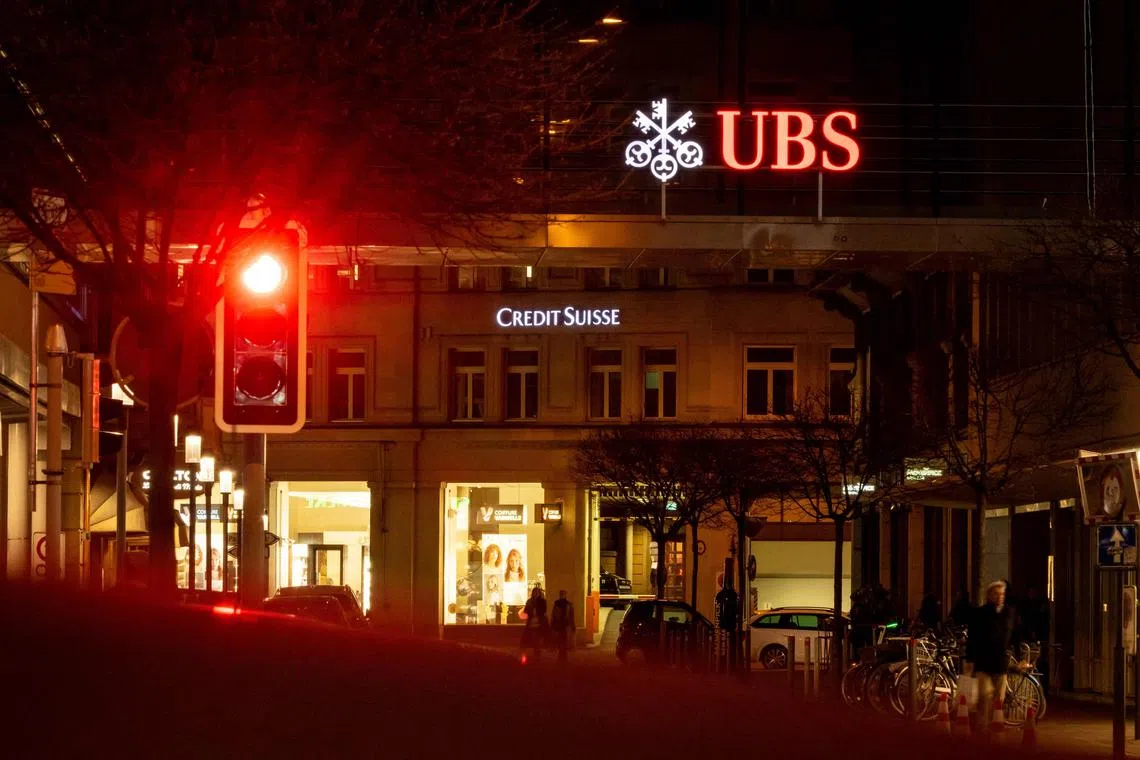 A sign of Credit Suisse bank is seen behind a sign of Swiss banking giant UBS in Zurich on March 18, 2023. - Switzerland's largest bank, UBS, is in talks to buy all or part of Credit Suisse, according to a report by the Financial Times. Credit Suisse -- Switzerland's second-biggest bank -- came under pressure this week as the failure of two US regional lenders rocked the sector. (Photo by Fabrice COFFRINI / AFP)