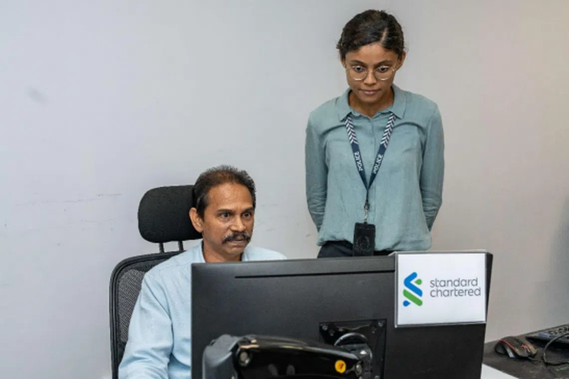 Mr Rajendaran S/O Rajoo, Fraud Risk Management manager at Standard Chartered (left), performing analysis work with ASP Nur Farhanah, Senior Investigation Officer at the Singapore Police Force's Anti-Scam Centre (right).
