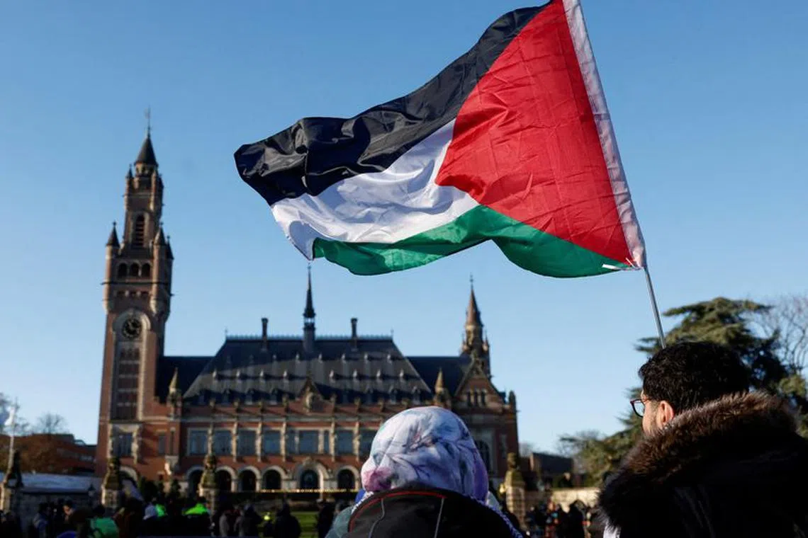 FILE PHOTO: Protesters hold a Palestinian flag as they gather outside the International Court of Justice (ICJ) as judges rule on emergency measures against Israel following accusations by South Africa that the Israeli military operation in Gaza is a state-led genocide, in The Hague, Netherlands, January 26, 2024. REUTERS/Piroschka van de Wouw/File Photo