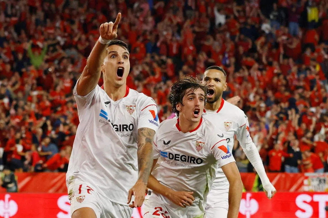 Sevilla's Erik Lamela celebrates scoring their second goal with Bryan Gil and Youssef En-Nesyri.