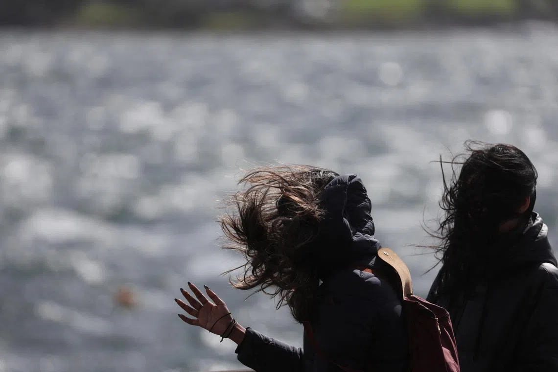 Women walk on the esplanade, as Storm Floris hits Scotland, in Oban, Britain August 4, 2025. REUTERS/Russell Cheyne