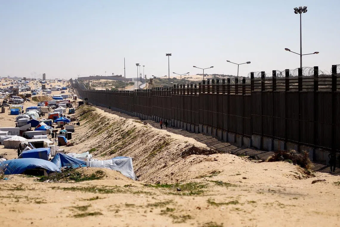 FILE PHOTO: People walk near the border with Egypt, as displaced Palestinians, who fled their houses due to Israeli strikes, shelter at a tent camp, amid the ongoing conflict between Israel and the Palestinian Islamist group Hamas, in Rafah in the southern Gaza Strip, February 29, 2024. REUTERS/Ibraheem Abu Mustafa/File Photo